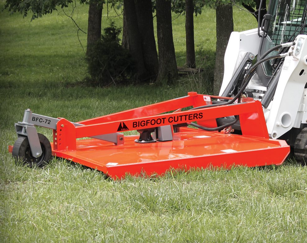 orange bigfoot cutter in use in grassy field